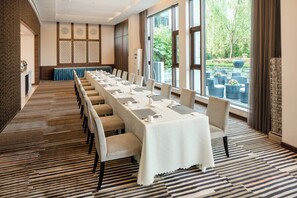 Un salón de conferencias con una larga mesa, sillas y vistas al exterior.