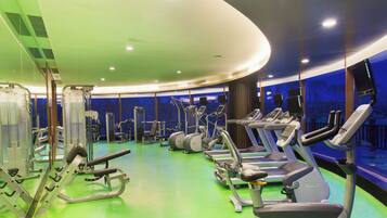 Uma academia com diversos equipamentos de exercício, incluindo esteiras e aparelhos de musculação, e piso verde.