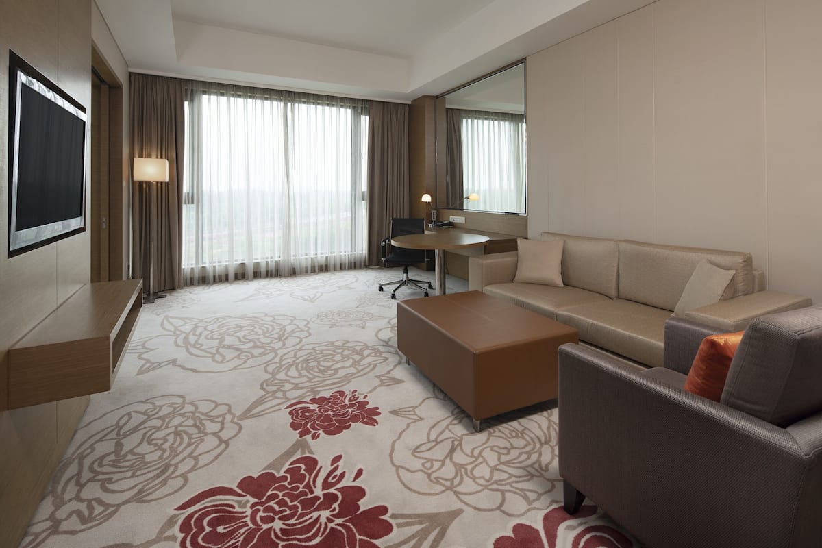 A hotel room with a large bed, a sofa, a coffee table, a desk, and a large mirror.