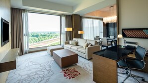 Une chambre d’hôtel avec une grande fenêtre, un canapé, un bureau et une chaise.