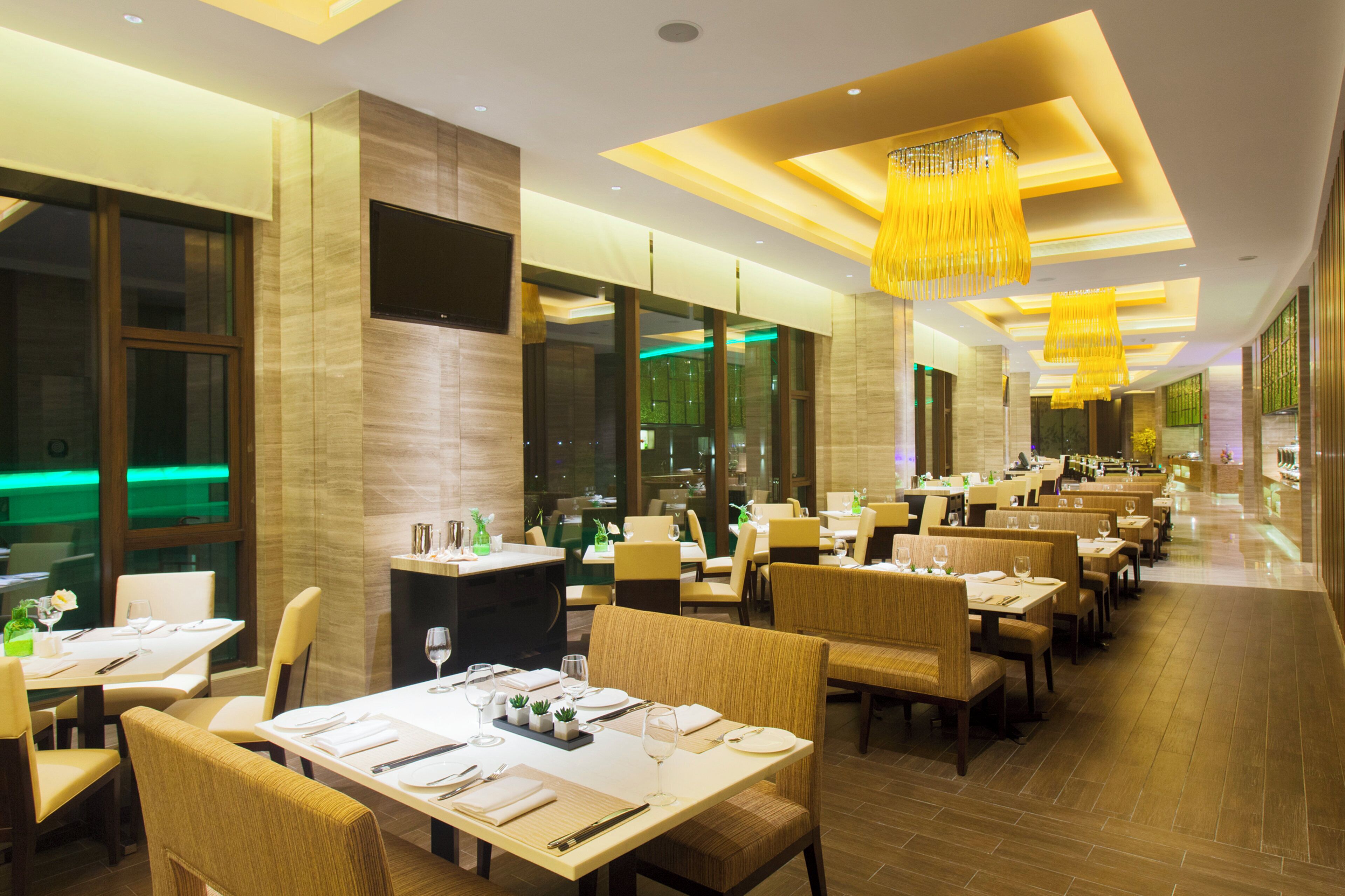 Un restaurante espacioso con varias mesas y sillas, ventanas amplias e iluminación moderna.