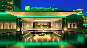 Un hotel con una entrada moderna, una piscina y un cartel que indica que es un Holiday Inn.