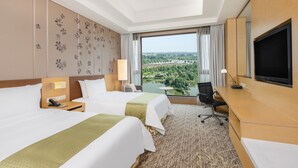 Une chambre d’hôtel avec deux lits, un bureau, une télévision et une vue sur le paysage urbain.