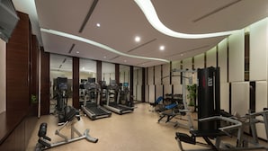 Ett modernt gym med löpband, styrketräningsmaskiner och en vägg med speglar.