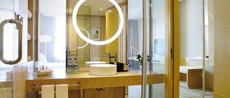 Une salle de bain moderne avec un grand miroir, un miroir rond et une cloison en verre.