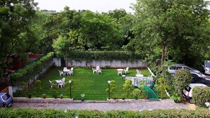 Een verzorgde tuin met gazon, zitgedeelte en een trap naar een hoger gelegen niveau.