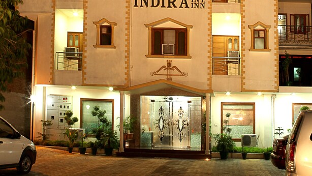 A multi-story hotel with a central entrance, balconies on each floor, and a sign reading "INDIRA INT. NN".