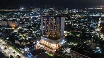 Un hotel moderno de gran altura, rodeado por una zona urbana densamente poblada de noche.