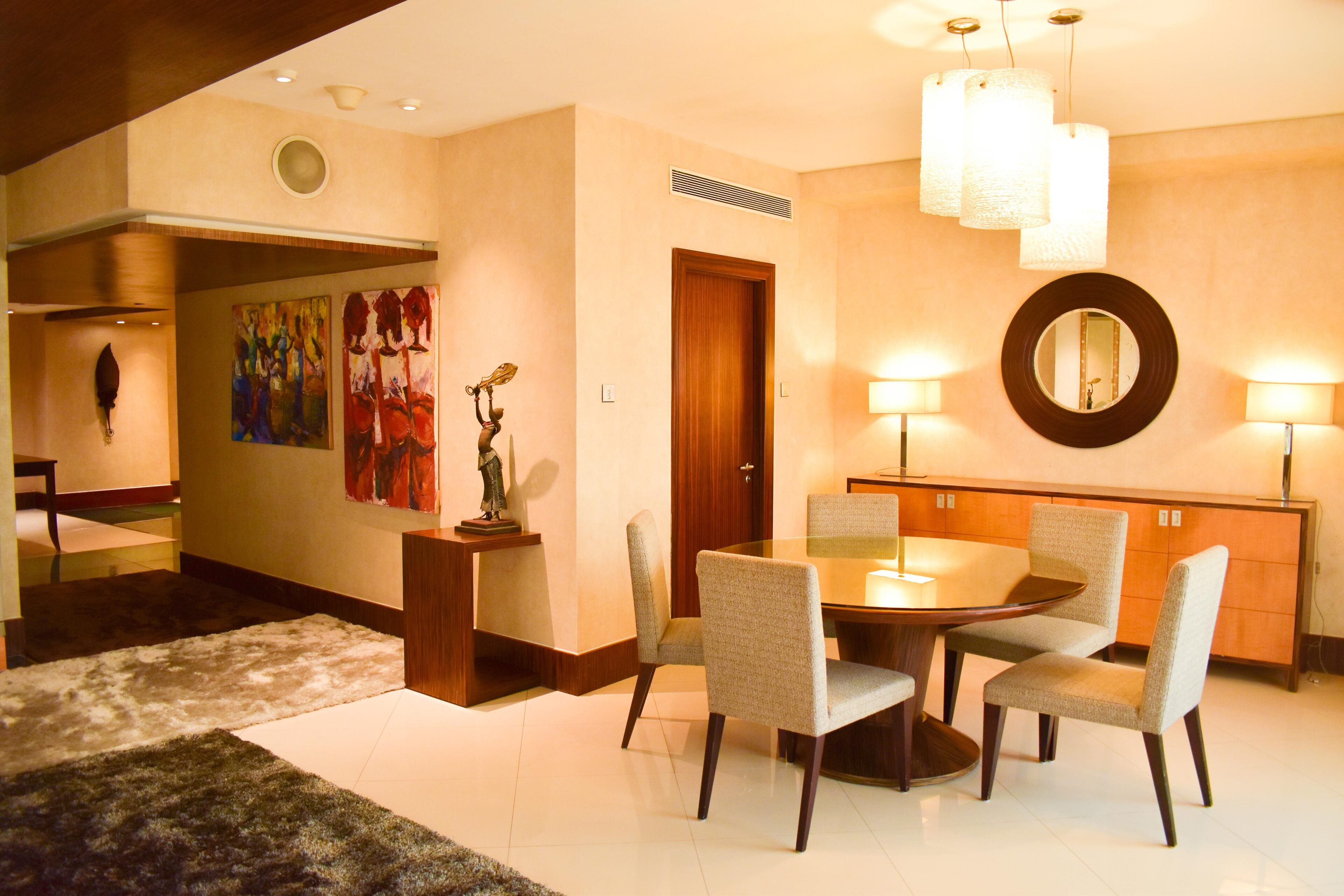 A modern dining area with a round table, four chairs, and a wooden cabinet.