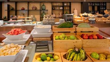 Un bufé con diversas frutas y verduras expuestas en cajas y bandejas de madera.