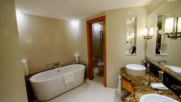 A modern bathroom with a freestanding bathtub, two sinks, and a large mirror.
