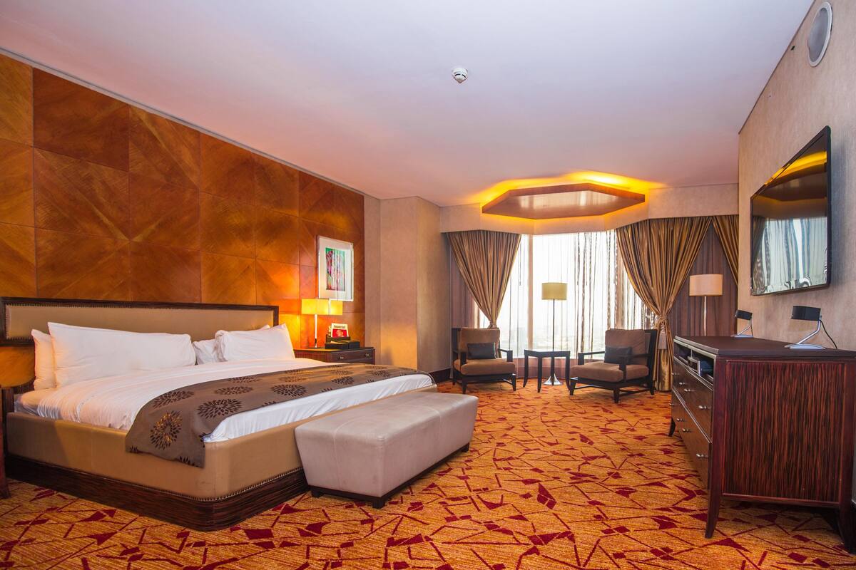 A hotel room with a large bed, a desk, a chair, and a television.