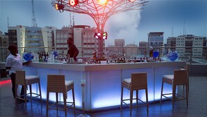 A bar area with a modern design, featuring a central bar counter and four wicker chairs. - Lagos Continental Hotel (Lagos)