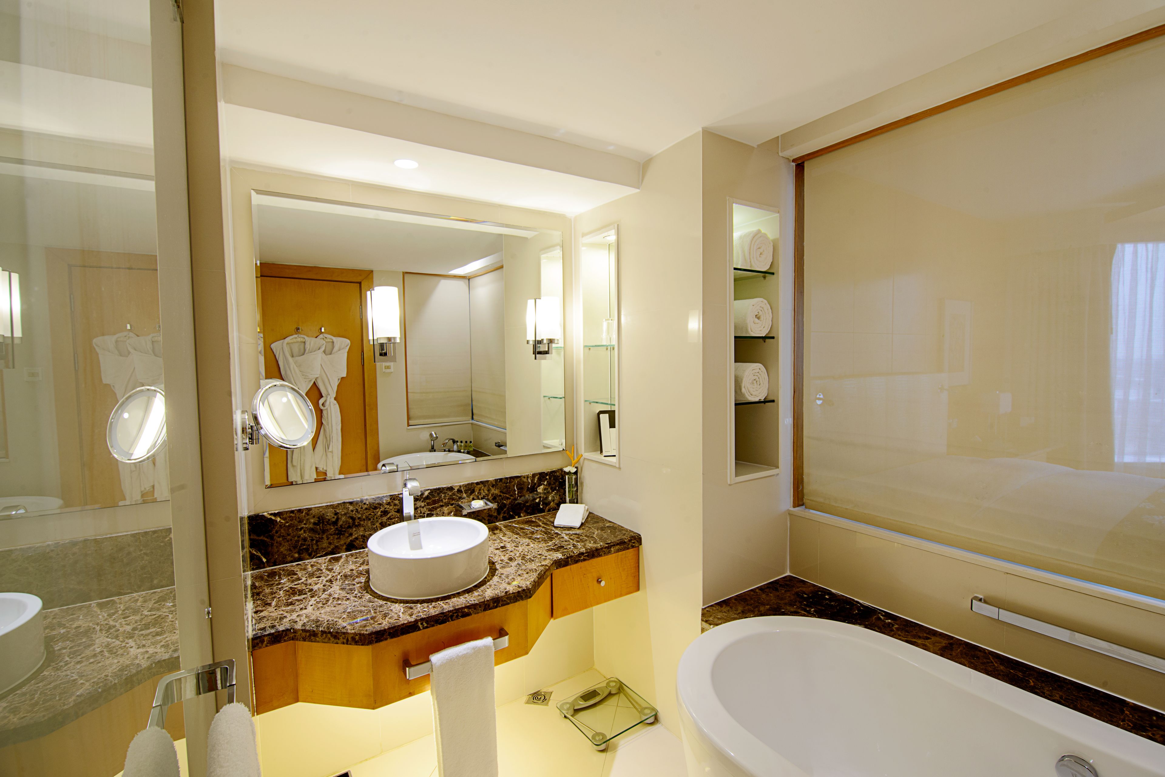 Ein modernes Badezimmer mit Marmorplatte, Waschbecken, großem Spiegel und Badewanne.