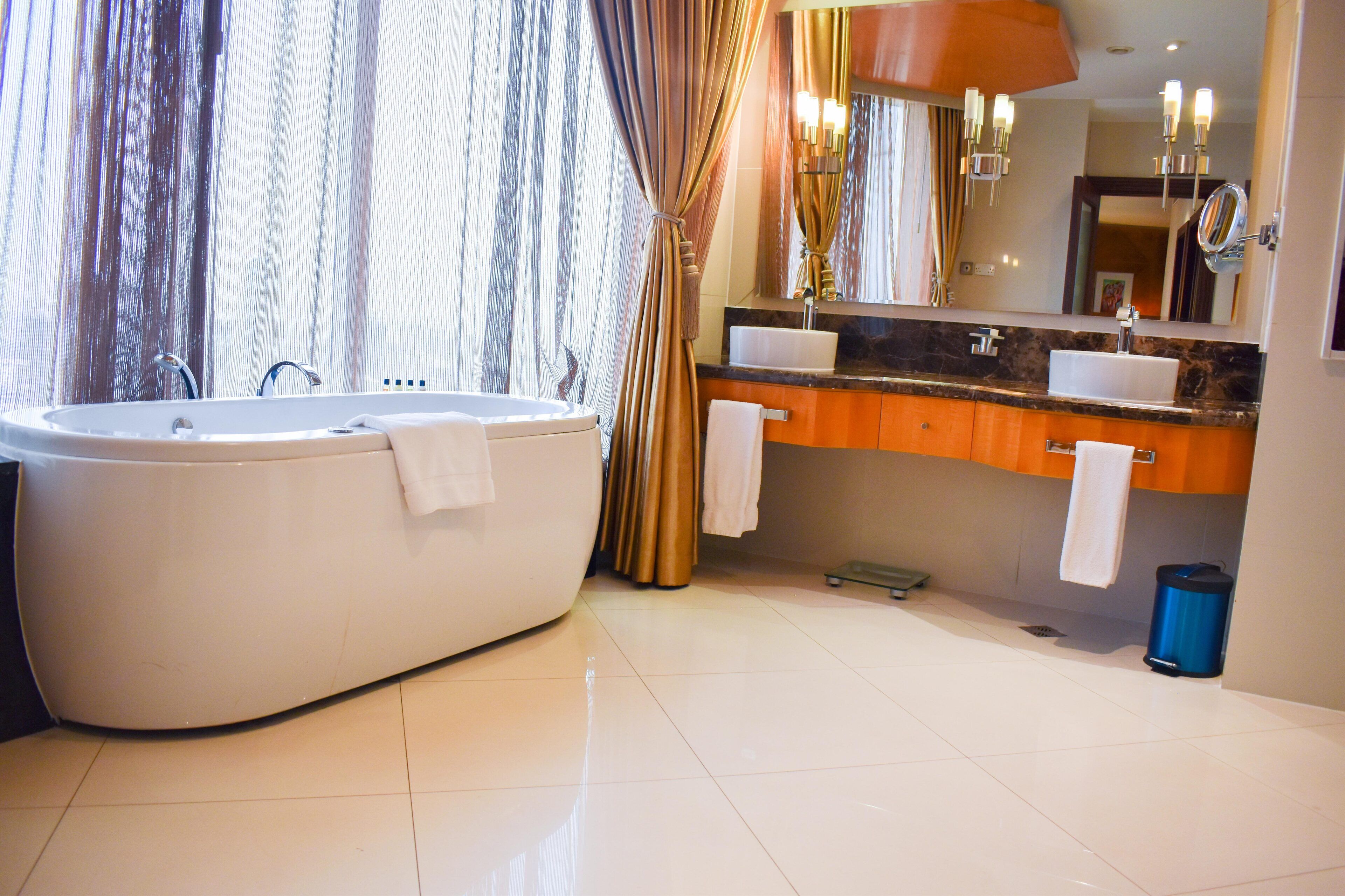 A modern bathroom with a freestanding bathtub, a vanity with a sink and mirror, and a large window with curtains.