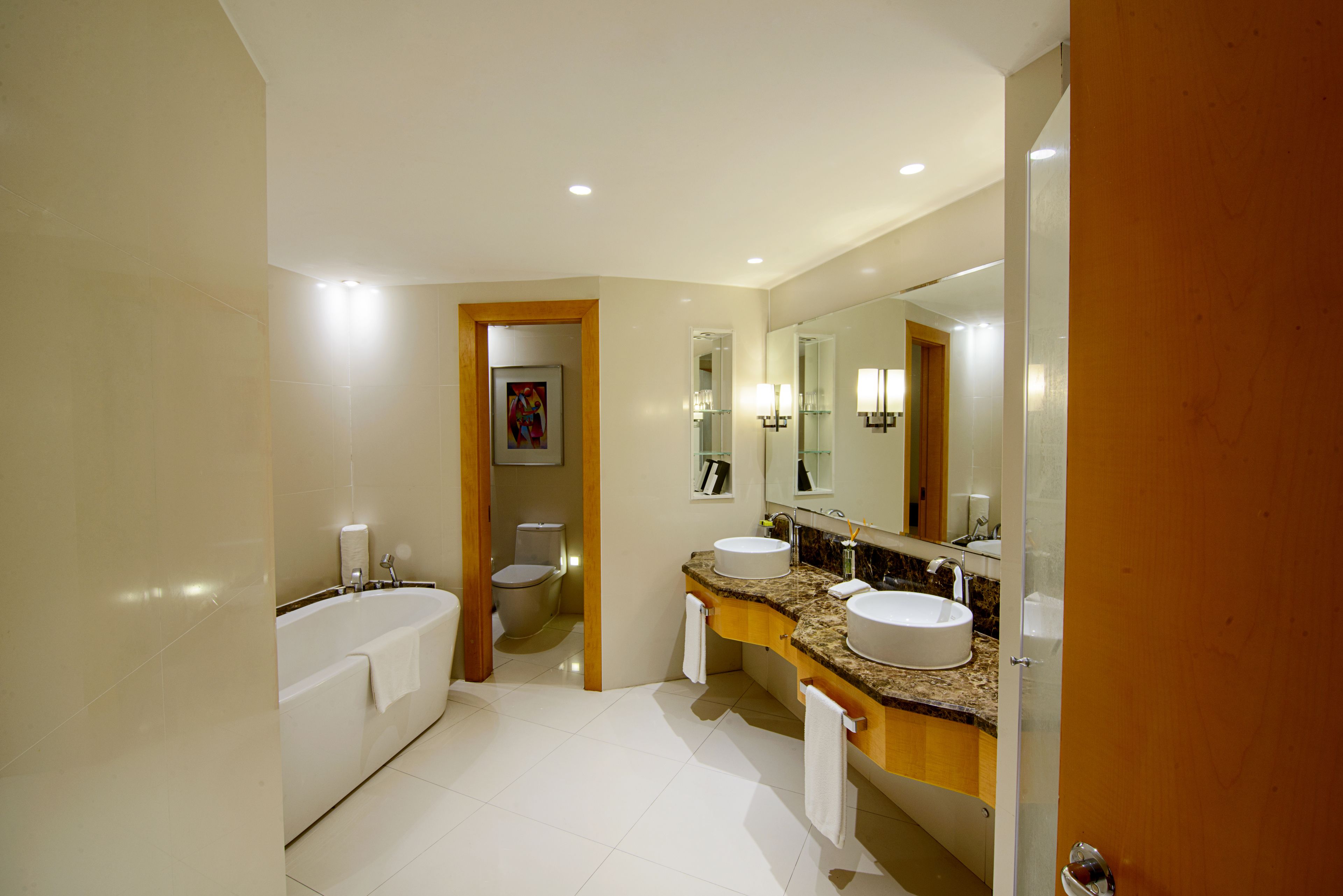 A modern bathroom with a bathtub, two sinks, and a large mirror.