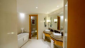 A modern bathroom with a bathtub, two sinks, and a large mirror.