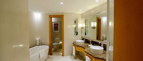 A modern bathroom with a bathtub, two sinks, and a large mirror.