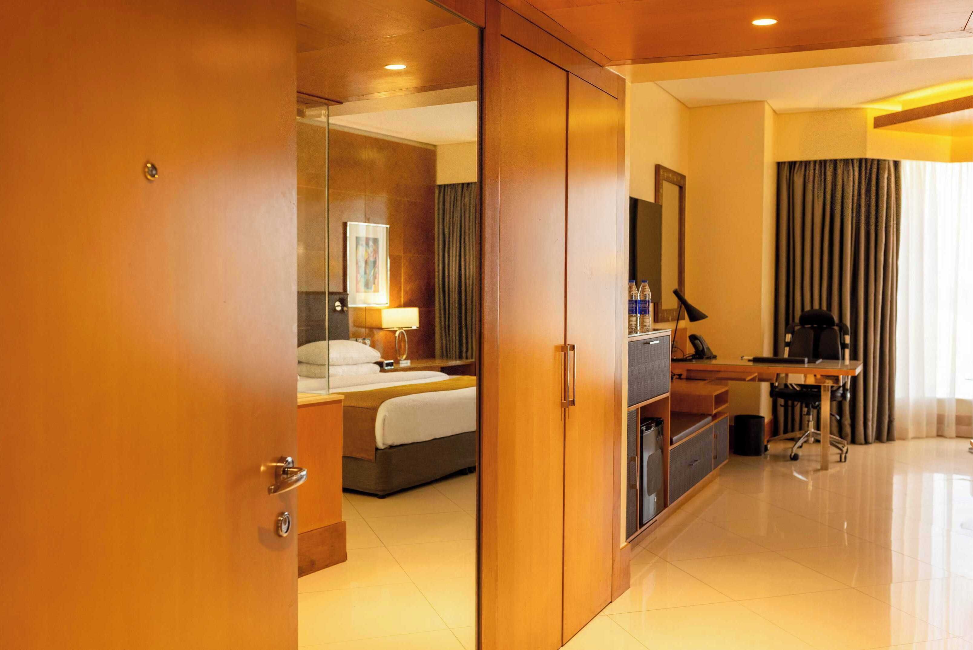 Une chambre d’hôtel comprenant un lit, un bureau, une chaise, un miroir et une armoire.