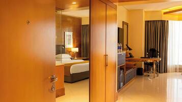 Une chambre d’hôtel comprenant un lit, un bureau, une chaise, un miroir et une armoire.