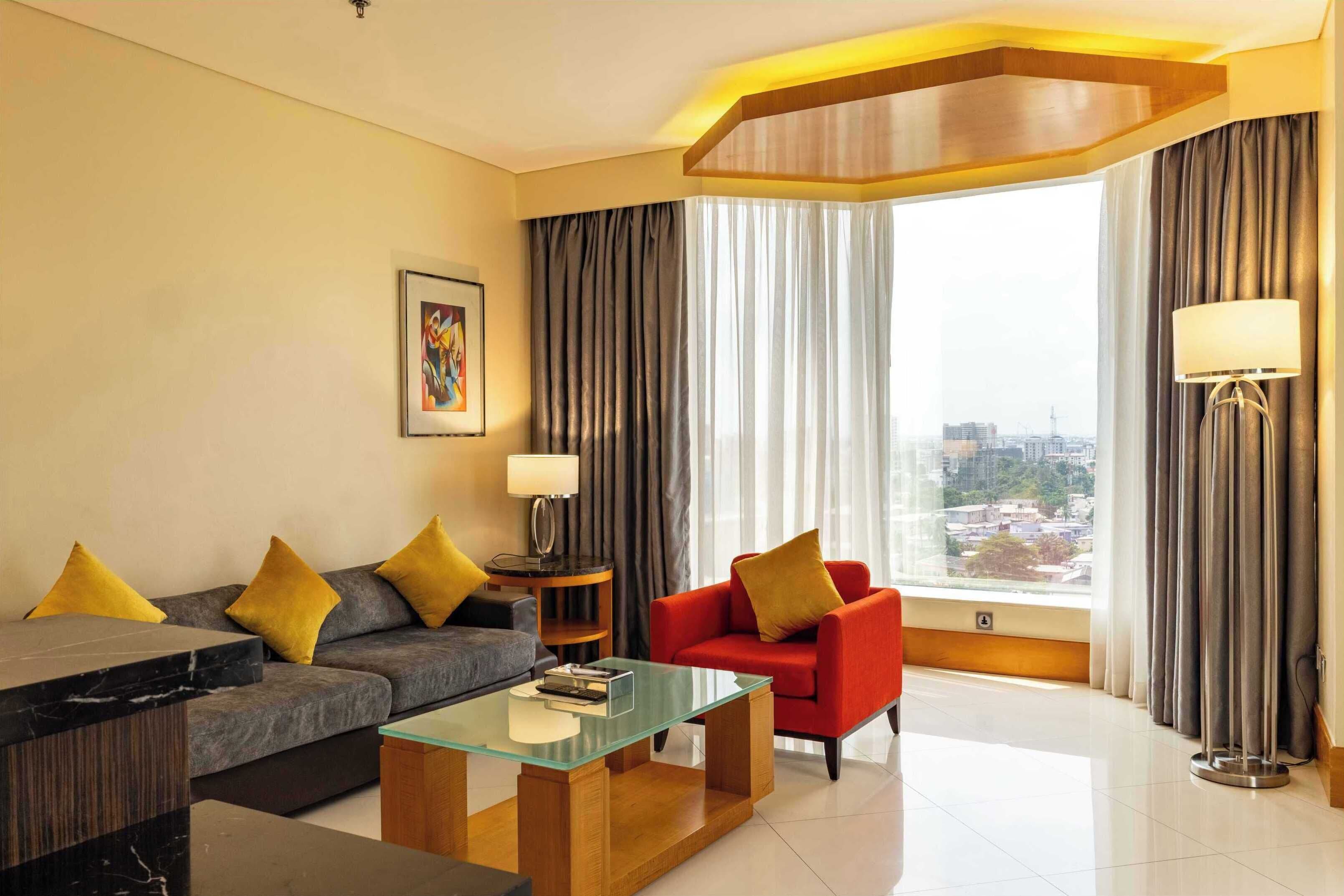 Ein modernes Hotelzimmer mit einer Couch, einem Sessel und einem Glastisch.