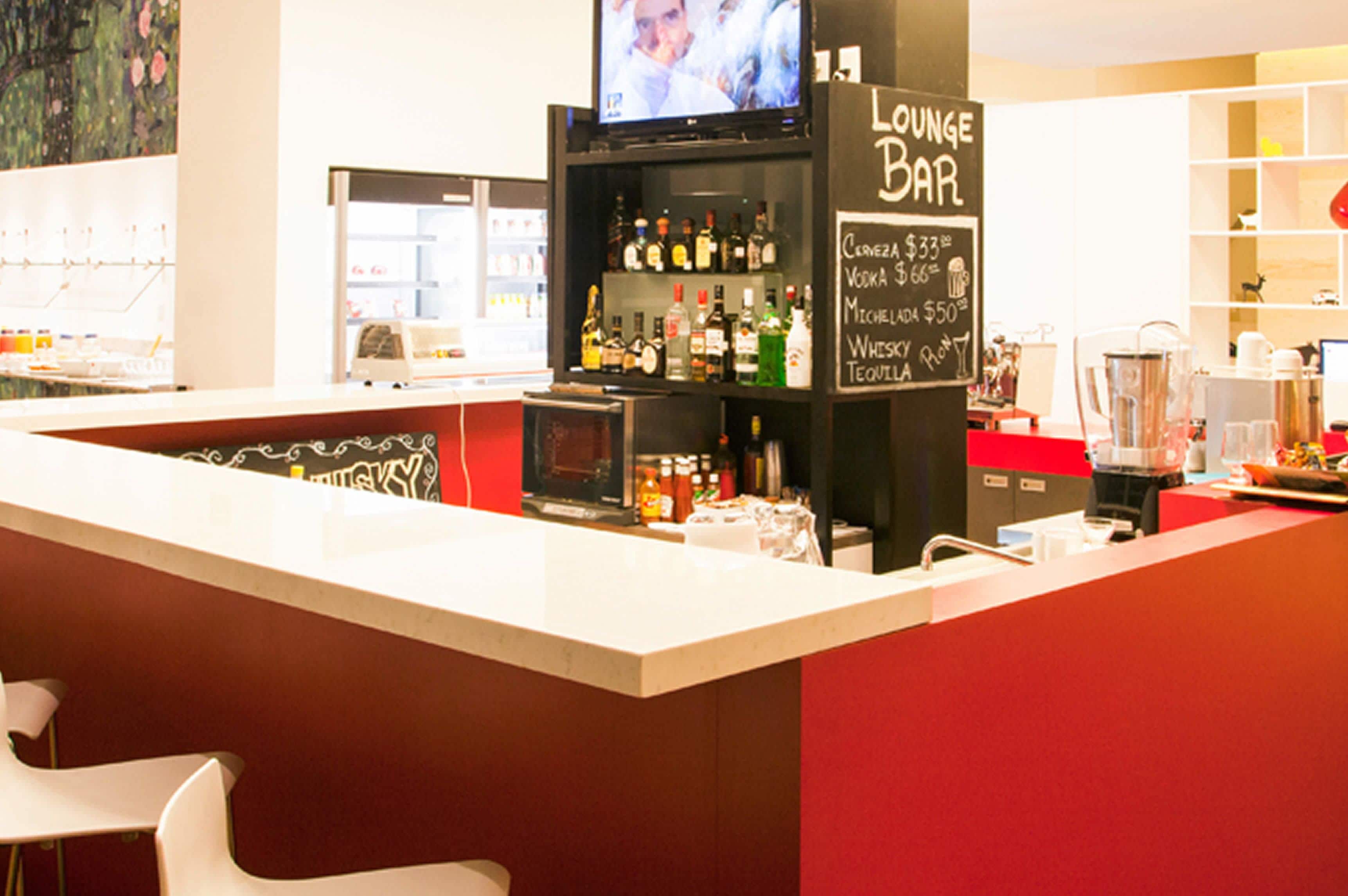 A bar area with a counter, shelves of liquor, a television, and a chalkboard menu.