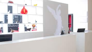 Un'area reception con un bancone bianco, scaffali con diversi oggetti e un grande murale.