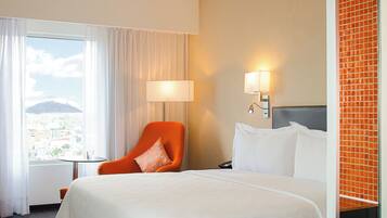 Een hotelkamer met een bed, een stoel, een lamp en uitzicht op een berg.