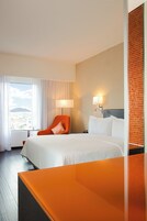 Een hotelkamer met een bed, een stoel, een lamp en uitzicht op een berg.