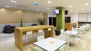 Un comedor moderno con una recepción, mesas y sillas blancas.