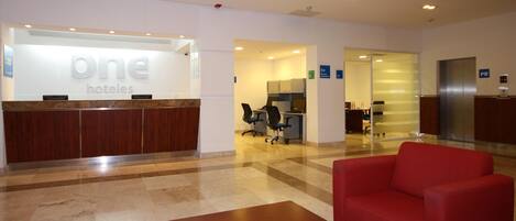 A hotel reception area with a reception desk, a red sofa, and a waiting area.