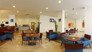 Un hall d’hôtel comprenant des espaces aménagés avec des sièges, un comptoir d’accueil et un écran de télévision.