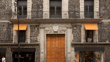 Un edificio histórico con una puerta de madera grande, dos balcones y fachada de ladrillo.