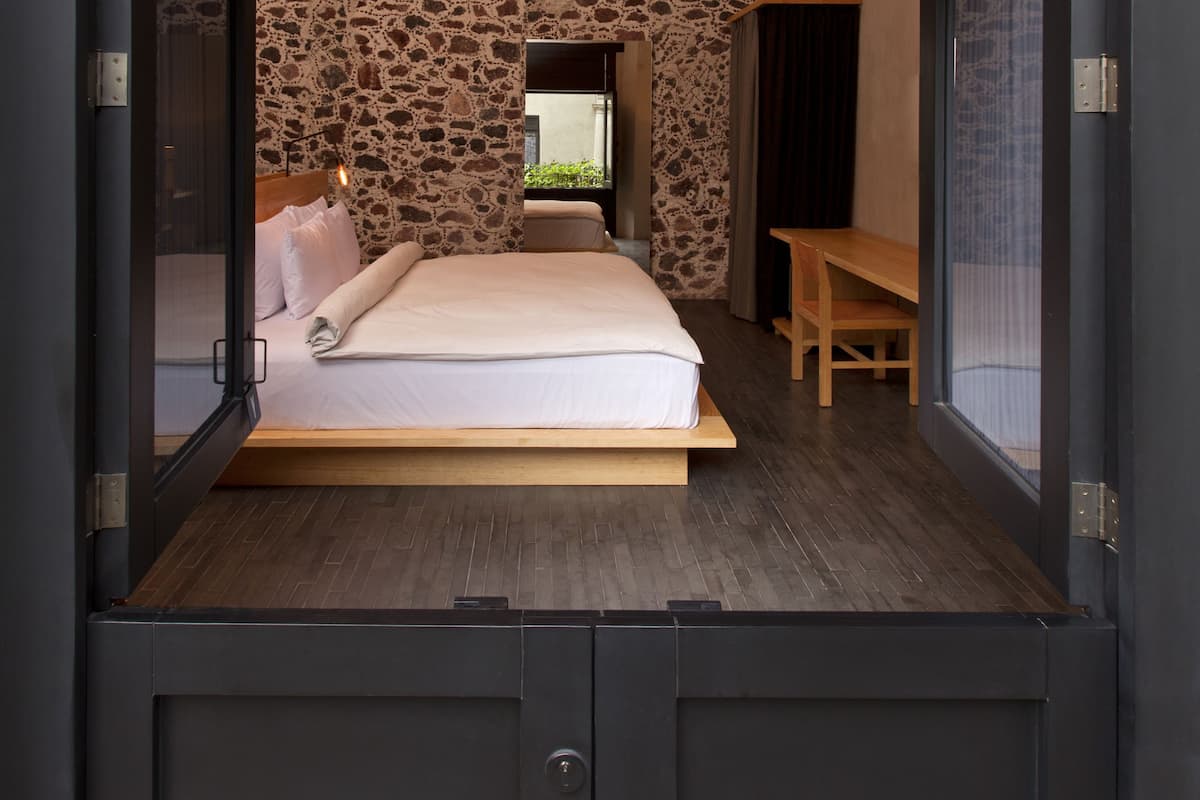 Une chambre avec un mur en pierre, un lit, un bureau et un téléviseur.