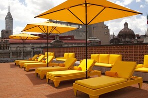 Una piscina al aire libre, sombrillas, sillones reclinables de piscina