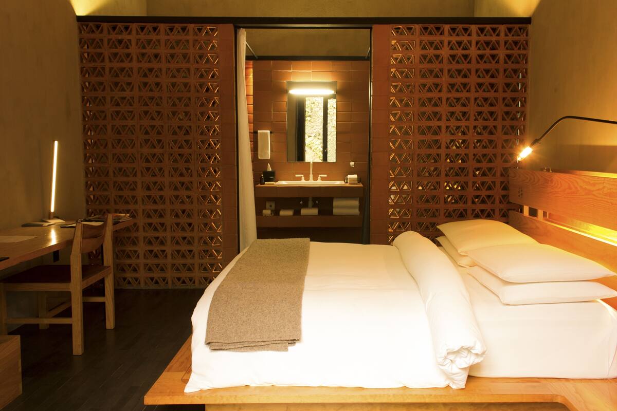 Une chambre d’hôtel comprenant un lit, un bureau, une chaise, une salle de bain avec un miroir et une douche.