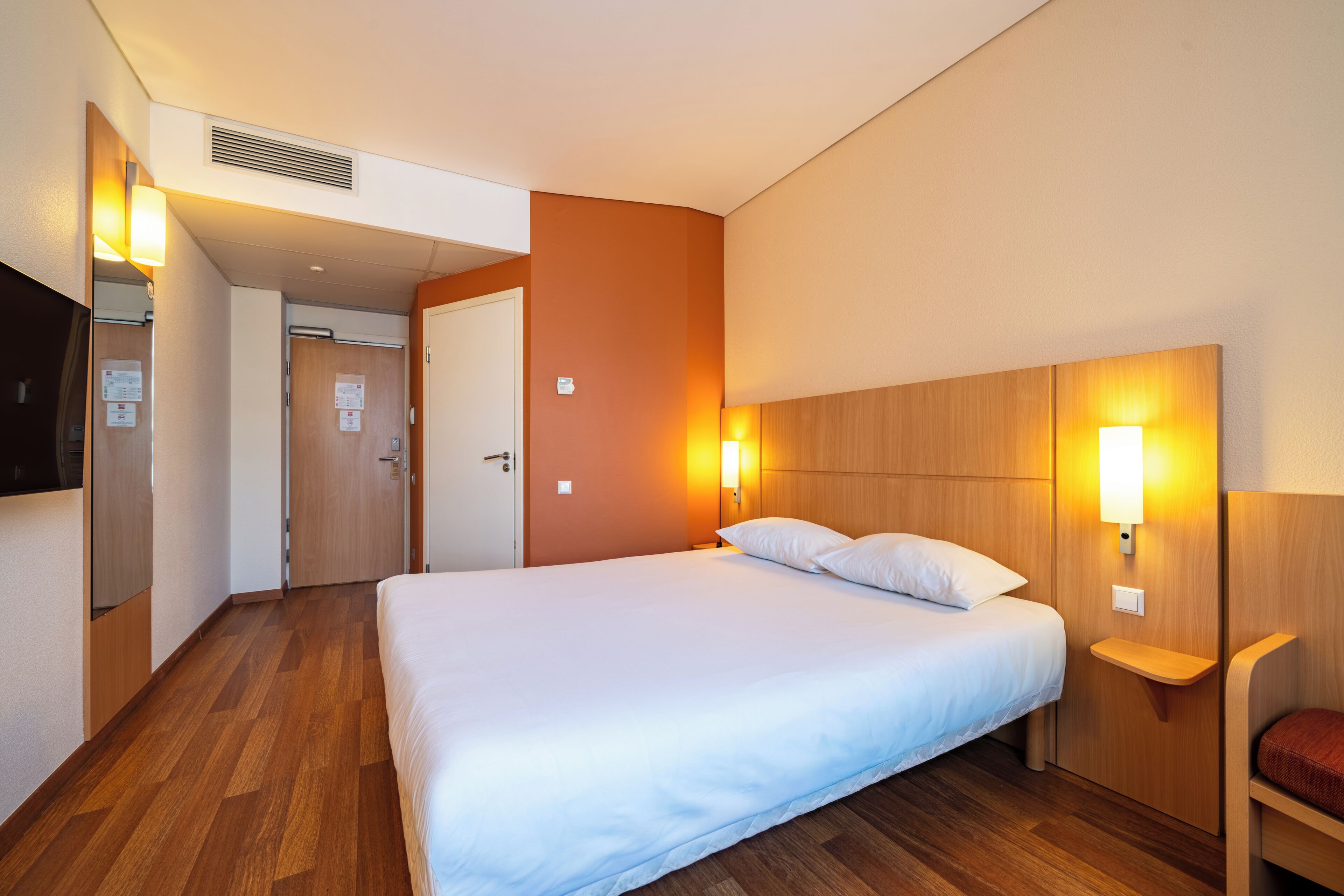Ein Hotelzimmer mit einem großen Bett, einem Holz-Kopfteil, Nachttischen und einem Flachbildfernseher.