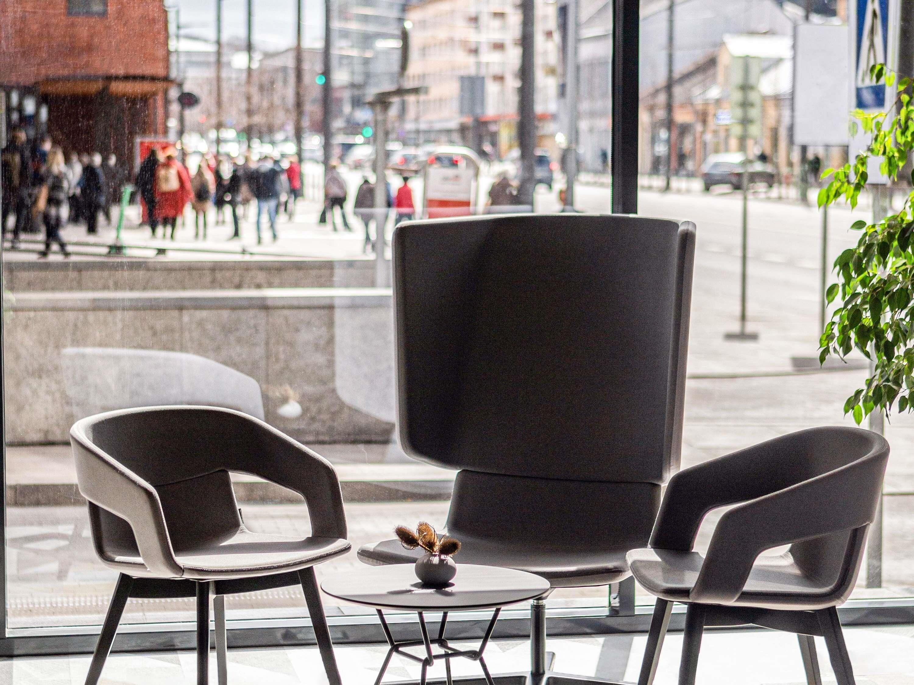 An indoor seating area with modern chairs and a small table, large windows with a view of a busy street.