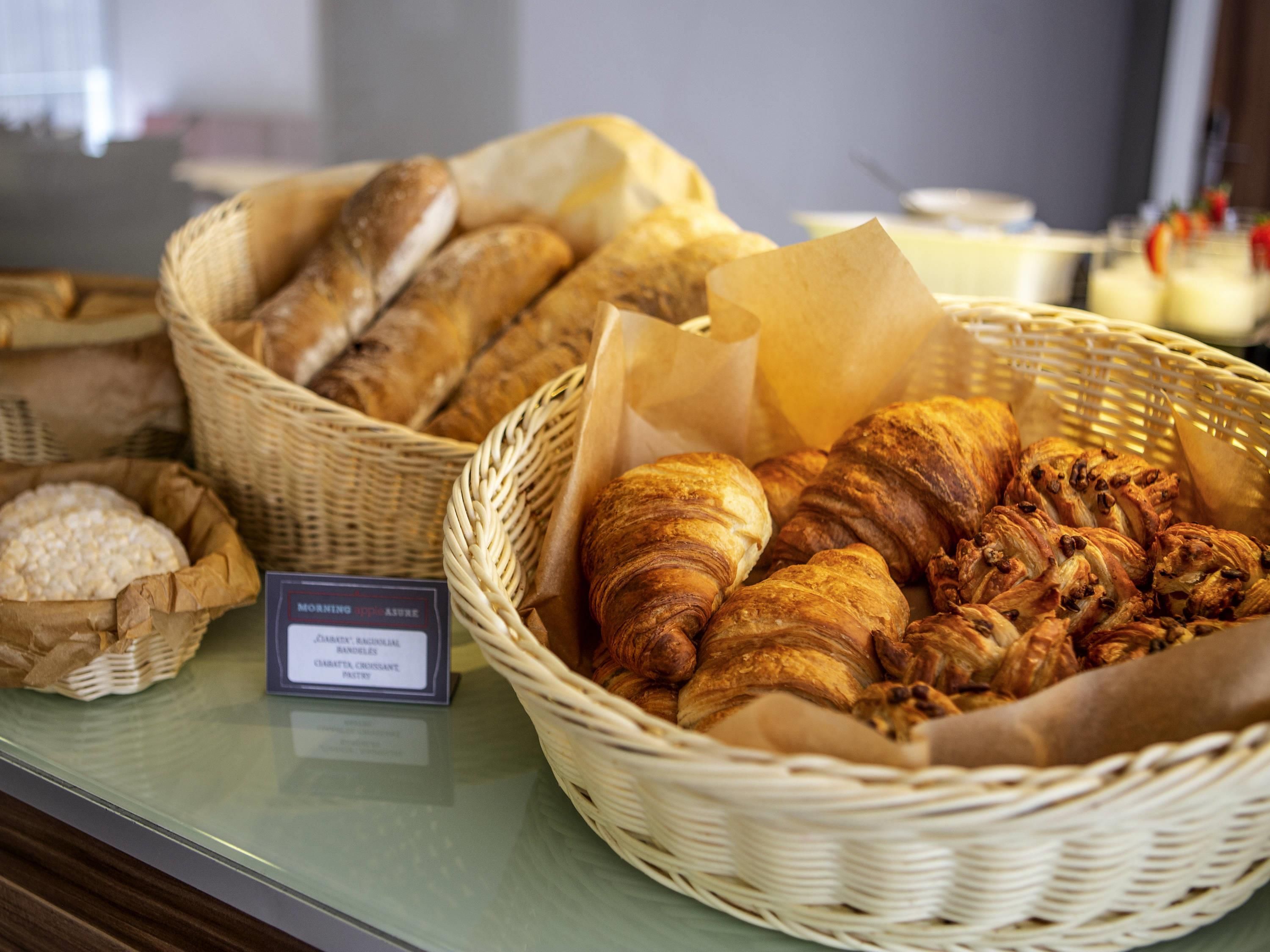 Una exhibición de productos horneados varios, como pan y pasteles, dispuesta en cestas de mimbre.
