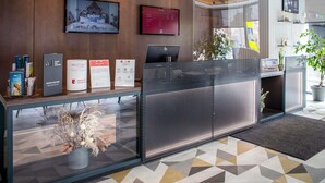 A reception desk with a computer, informational signs, and a plant. - ibis Kaunas Centre (Kaunas)