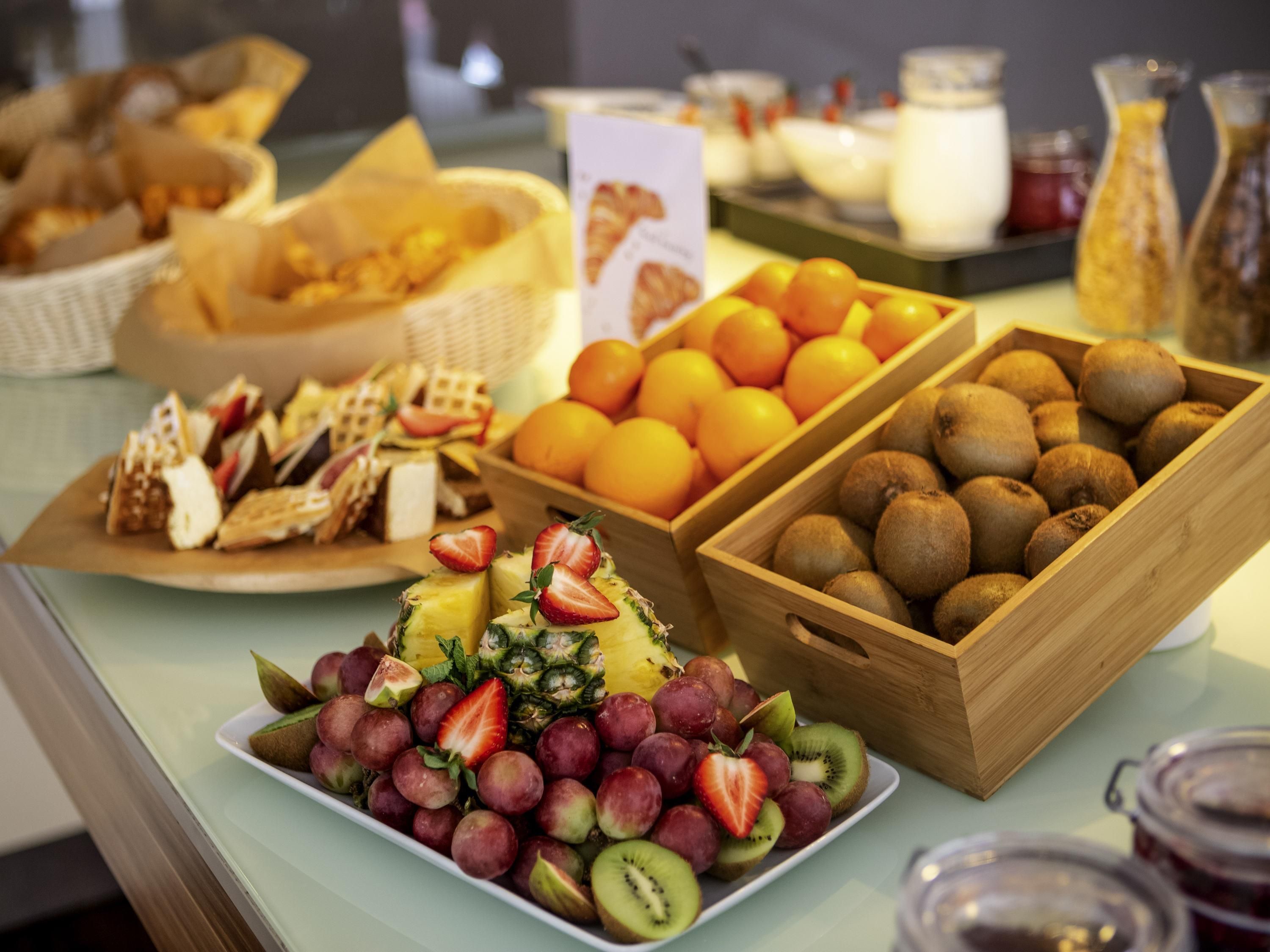 A buffet with various fruits, pastries, and cheeses.