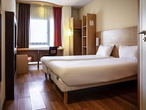 Habitación de hotel con cama doble, un escritorio, una silla y un armario.