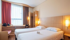 A hotel room with two beds, a desk, a chair, and a wardrobe. - ibis Kaunas Centre (Kaunas)