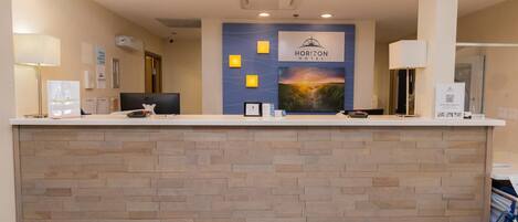 Un mostrador de recepción con el letrero de Horizon Hotel, un mapa y un monitor de computadora.