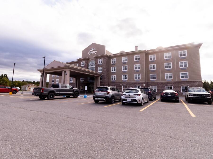 Un hôtel doté d’un parking où plusieurs voitures sont garées devant l’entrée.