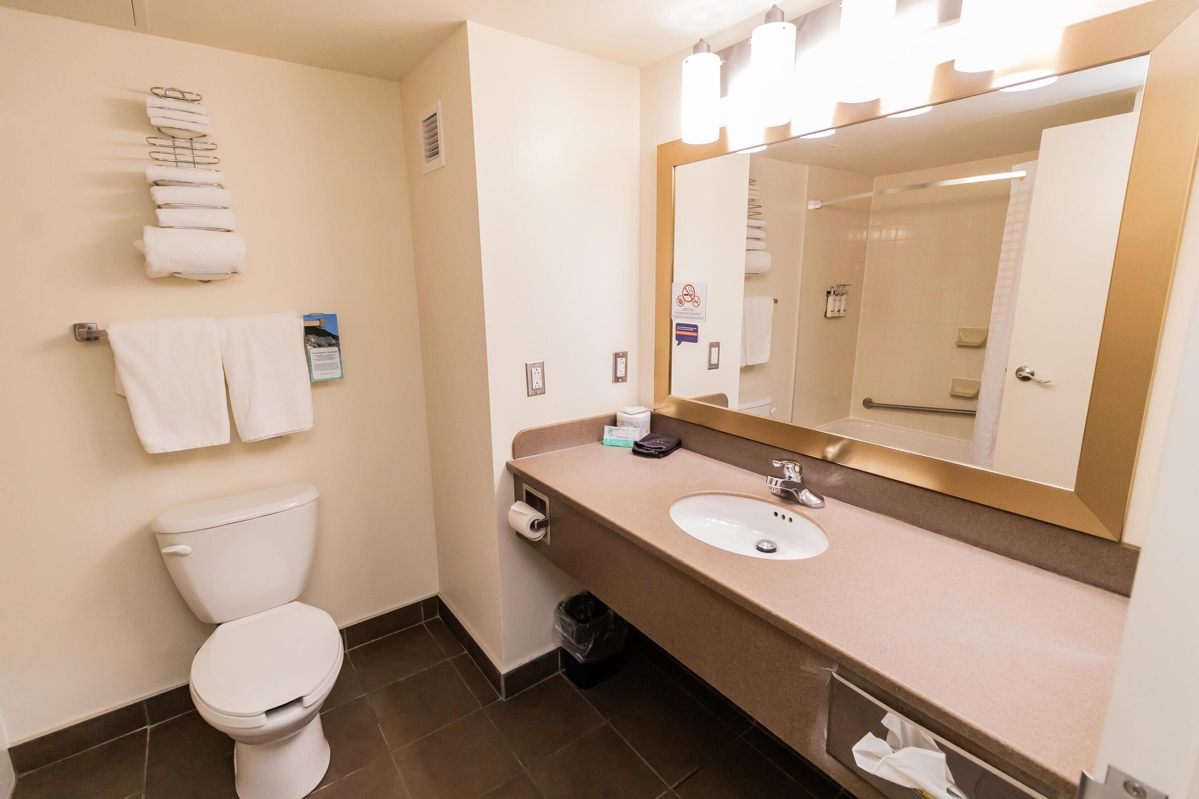 Een hotelbadkamer met toilet, wastafel en een spiegel met verlichting.
