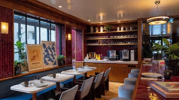 A restaurant with wooden paneling, a bar area with stools, and a display of teapots and cups.