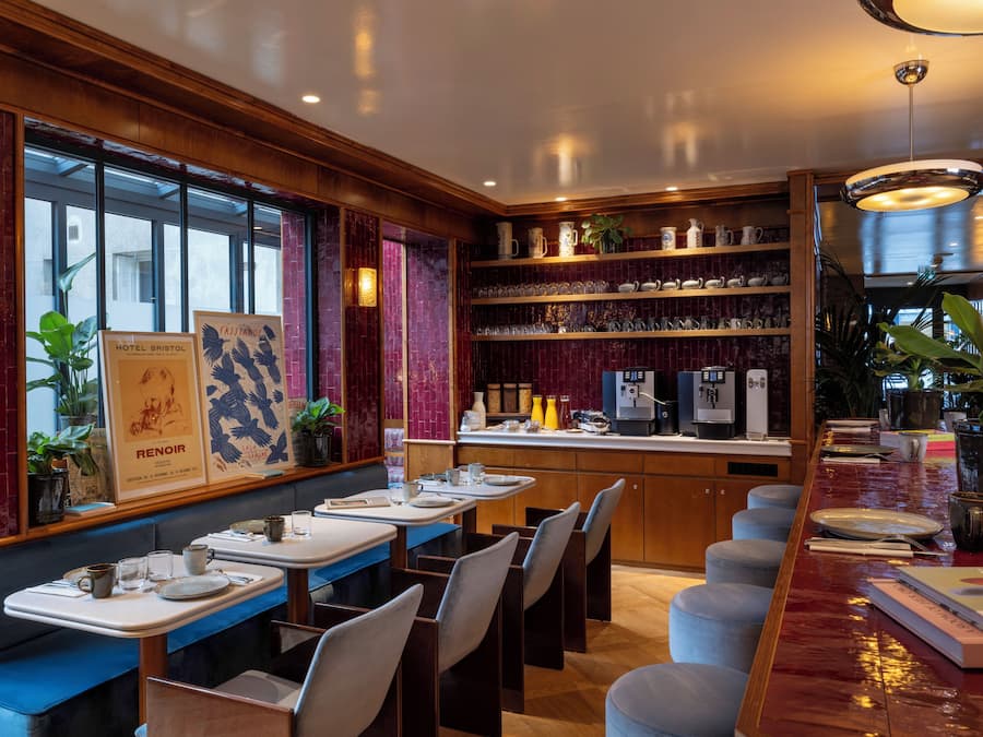 A restaurant with wooden paneling, a bar area with stools, and a display of teapots and cups.