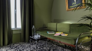 A room with a green sofa, a patterned rug, a small table with glasses, and a framed picture on the wall. - La Conversation (Paris)