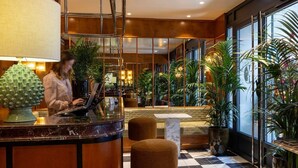 A hotel lobby with a reception desk, seating area, and large windows. - La Conversation (Paris)